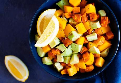 Bowl of chopped sweet potatoes, avocados and mangoes with slices of lemon