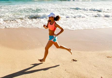 woman running barefoot on beach sand