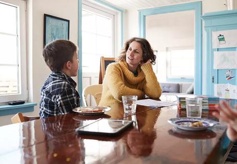 mother having serious conversation with son at kitchen table