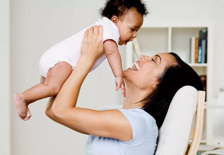 mother lifting baby overhead with laughter