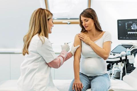 Healthcare provider giving pregnant patient a shot