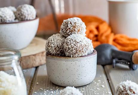 A small bowl of round apple cinnamon snack bites coated in coconut