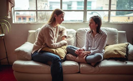 Adult having a serious talk with a child in living room on a couch