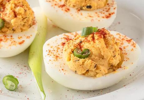 A close-up photo of deviled eggs with paprika sprinkled on top of mashed yolks