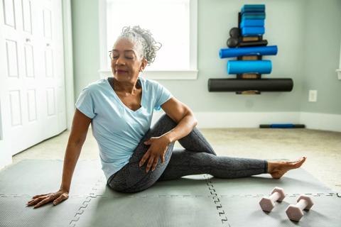 Person stretching on floor mats in their home gym area