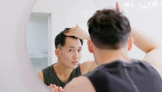 Person looking in mirror, checking their hairline