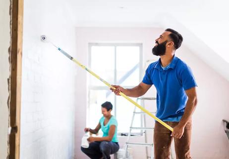 man and woman painting walls inside home