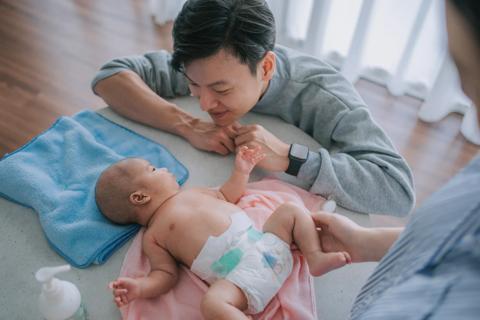 Caregivers adoring baby in diaper on diaper changing table