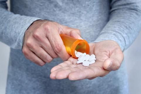 Person shaking pills into their hands
