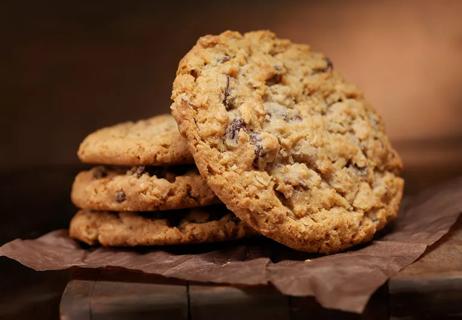 Cloaseup of oatmeal maple raisin cookies displayed on napkin and wooden table.
