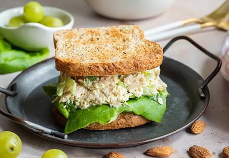 A curried chicken salad sandwich is displayed on a black plate.