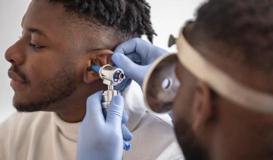 Eye care provider checking a patient's ear with an otoscope