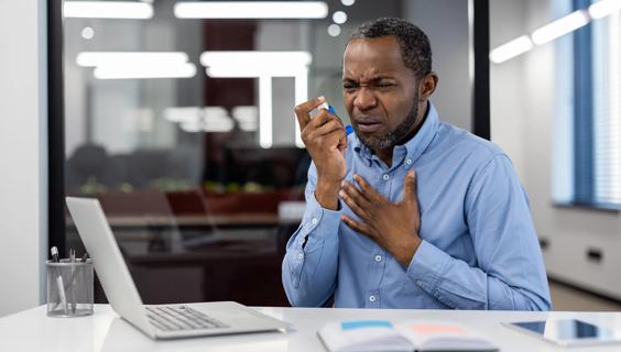 Person having an asthma attack at work, using inhaler