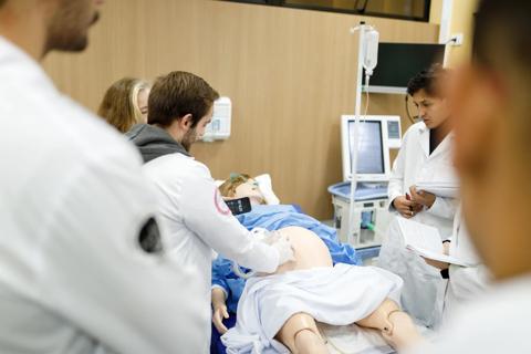 medical team surrounding a hospital bed with a "pregnant" medical manikin