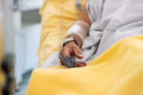 Close-up of a male patient&#8217;s hand in a hospital bed with oximeter