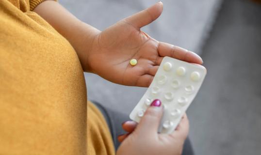 Person holding a pill from a blister pack of medication