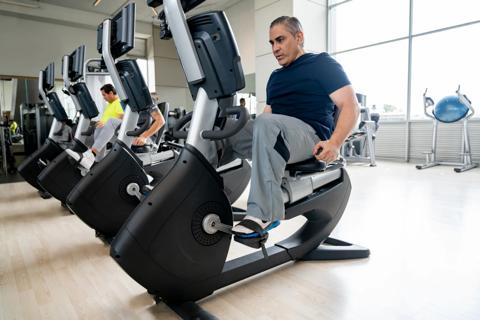 Person using recumbent stationary bike at gym facility