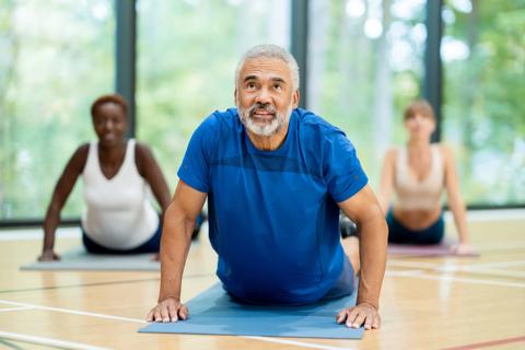 Older person doing stretches on mat during a fitness class