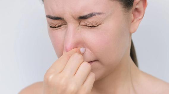 Woman gently pinching ends of nose together