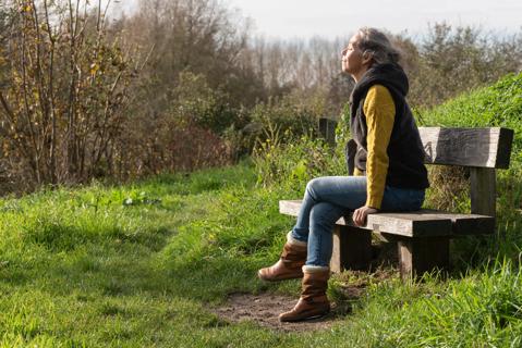 Person sitting outside on park bench, taking in the fresh air and sunshine