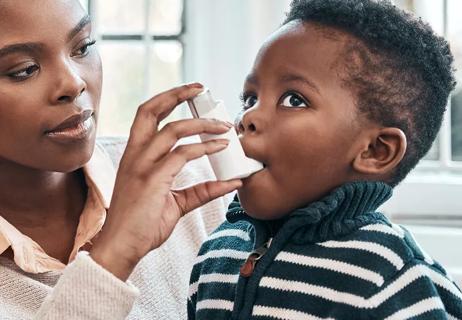 Parent helps child with their inhaler at home.