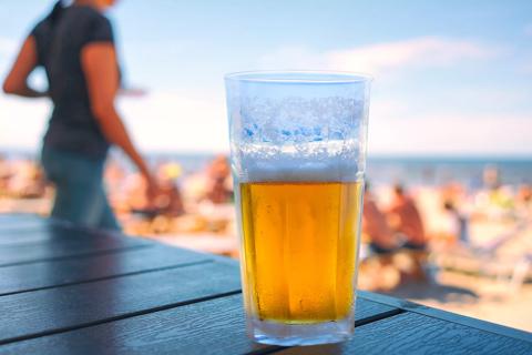 Glass of beer on table at beach with beach-goers