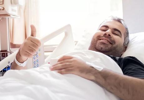 Man in hospital bed after organ donation - thumbs up