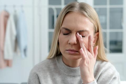 Person with eyes closed, rubbing one eye