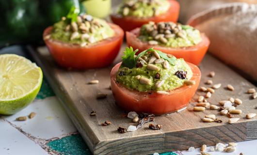 Tomatoes stuffed with poblano peppers and avocado on cutting board, with line and pumpkin seeds scattered