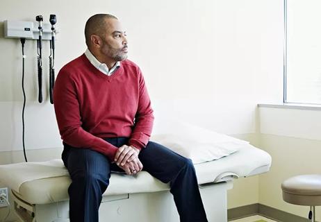 Male patient sitting on exam table in clinic room