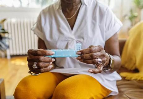 person taking vitamins from pill organizer