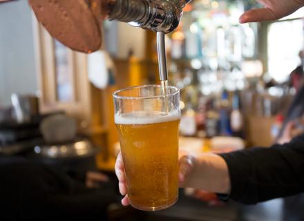 Glass of draft beer being poured at a pub