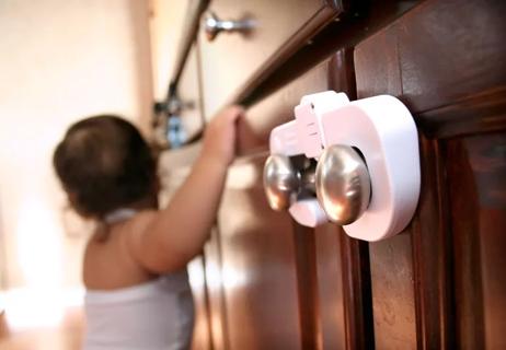 childproof locks on cupboard doors while toddler plays