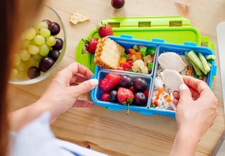 woman packing healthy lunch for her student athlete