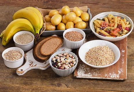 A table full of foods including bananas, pasta, bread and beans