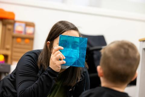 Caregiver holds object in front of face while engaging with child