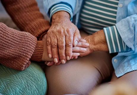 Two people holding hands in a comforting way