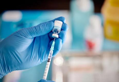 Gloved hand filling syringe with vaccine