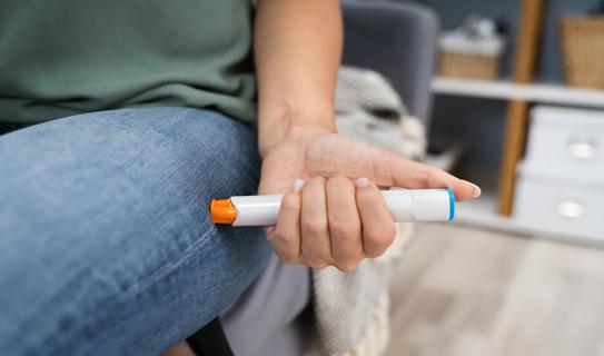 Person injecting EpiPen into thigh