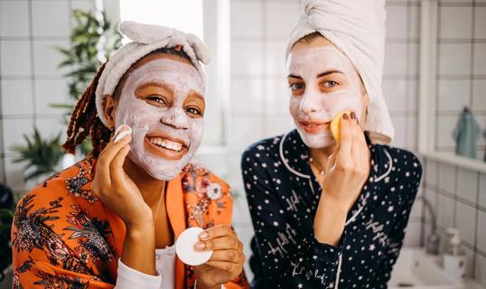 Two happy people in pjs with faces covered in white skin care products