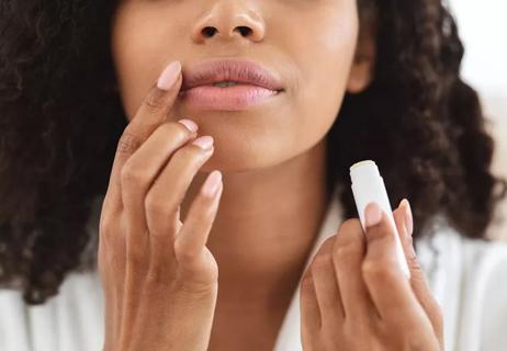 Person applying lip balm and smoothing it over lips after application.