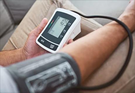 Person using electronic blood pressure monitor at home.