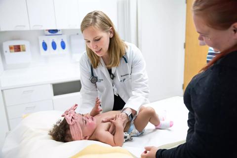 Physician caring for infant on exam table