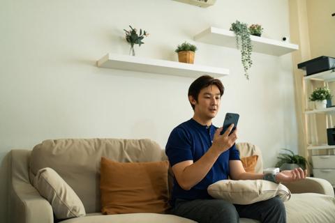 Person checking their blood pressure with a digital cuff and smartphone app at home