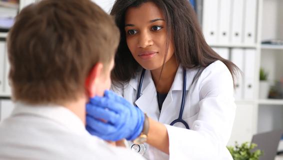 Healthcare provider feeling patient's neck with gloved hands