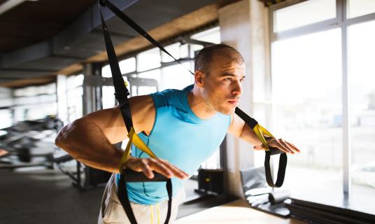 Person using TRX suspension trainer at gym