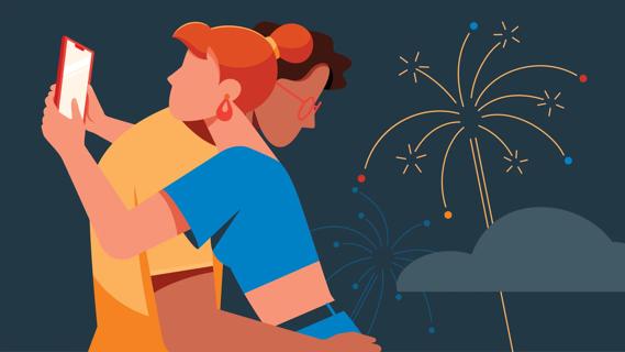 A couple hugging, with one of them looking at their phone, with fireworks in the background