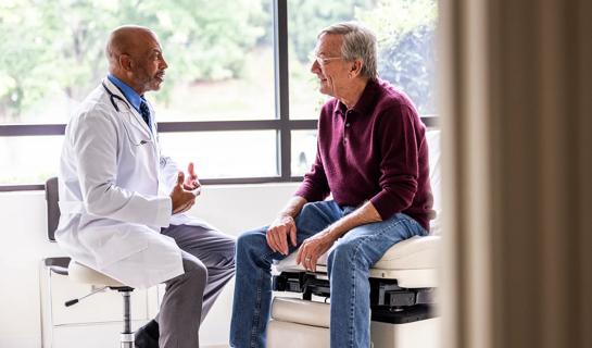 Healthcare provider and older patient talking in exam room
