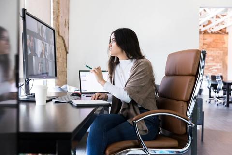 Person seated at office desk chair while on a virtual team call