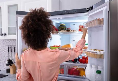 woman in refrigerator looking for food to eat